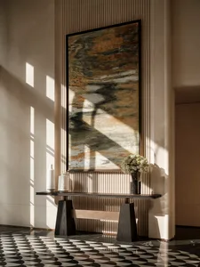 A well-lit room with a modern art piece on the wall, a vase, and a warm atmosphere