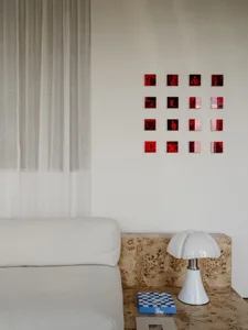 A well-lit living room with a white couch and a table with a lamp, set against a neutral background