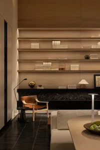 Cozy living room with a wooden floor, a couch, a chair, and a bookshelf with books, creating a warm and inviting atmosphere
