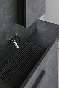 A modern kitchen counter with a stone surface and metallic sink, set in a dimly lit space