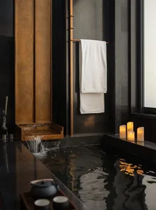 A modern bathroom with a large bathtub, shower, and dim lighting, featuring marble and glass surfaces