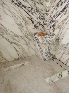 Marble bathroom with a marble countertop, wall, and floor, featuring a brown soap and a clean, elegant appearance