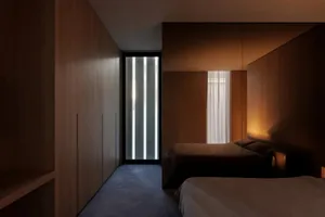 Cozy bedroom with a wooden floor, a bed, a closet, and a window, dimly lit