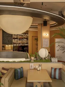 A cozy restaurant dining area with a table and chairs, surrounded by wood and metal elements, dim lighting, and various decorative items