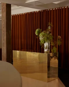 Dining area with a wooden countertop, brown curtain, and a vase with flowers on a table surrounded by chairs
