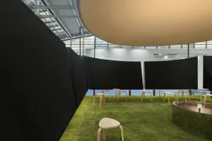 A modern living space with a grass floor, a large dome-shaped structure, and various chairs in different styles and sizes