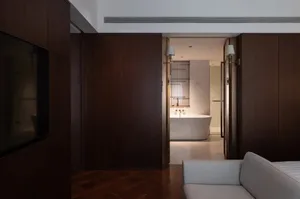 Cozy modern bathroom with a wooden floor, white bathtub, and dim lighting, featuring a seating area with a couch and chair
