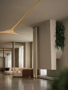 A modern living room with a couch, chair, and potted plant, featuring a large window and well-lit atmosphere