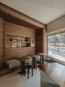 A warm and inviting room with wooden walls and floors, featuring a dining table, chairs, bookshelf, and counter