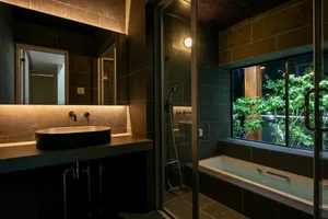 A dimly lit bathroom with a black and white bathtub, sink, and mirror, creating a moody and elegant atmosphere