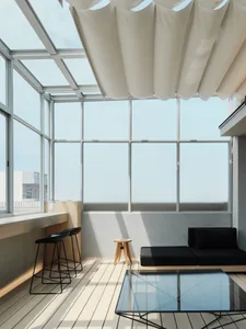 Cozy living room with a black couch near a large window, a wooden table, and a glass table in the center, surrounded by a modern style atmosphere