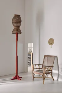 A dimly lit living space with a wooden chair and table, surrounded by a white wall and a red pole
