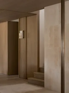 A dark and gloomy hallway with wooden walls, lined with doors and a light on the wall