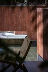 Cozy living space with a chair and couch, wooden floor, and brick wall, lit by natural sunlight