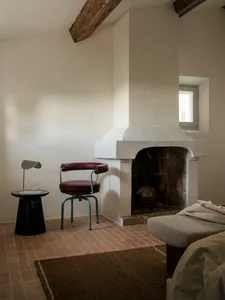 Cozy living room with a white interior, a fireplace, a couch, a chair, and a dining table, creating a warm and inviting atmosphere