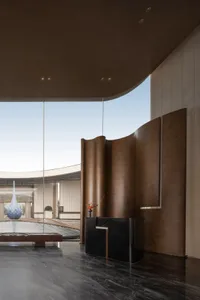 A modern lobby with a large glass wall, a circular glass sculpture, and soft diffused lighting creating a warm atmosphere