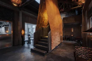 A restaurant with a stone wall, multiple chairs, and dining tables arranged throughout the room, creating an inviting and comfortable atmosphere