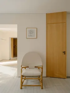 A modern living room with a white chair and wooden door, well-lit and inviting, with a focus on comfort and functionality