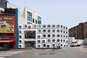 Photograph of a modern building with a circular shape and white facade in a busy urban city setting