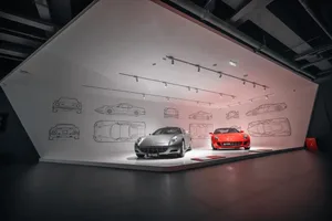 A modern sports car showroom with a white color scheme and red accents, featuring a row of sports cars under bright lights