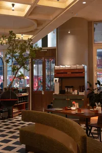 A cozy cafe interior with a wooden table and chairs, surrounded by decorative items and a potted plant, under soft warm lighting