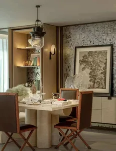 A modern living room with a dining table and chairs, surrounded by books and a potted plant, with a warm and inviting atmosphere