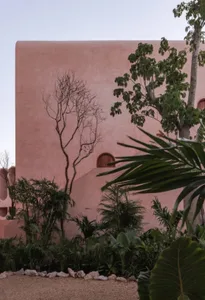 A pink building with a mix of architectural styles, featuring stone and concrete materials, under natural and artificial lighting