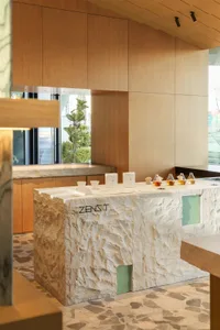 A modern kitchen or dining area with a marble counter, dim lighting, and several cups and bottles placed on the counter