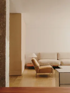 Cozy living room with a couch, chair, and table, featuring a wooden floor and white walls, with dim lighting