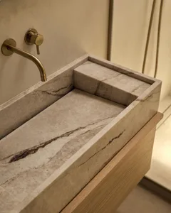 浴室內有大理石 countertop,金屬洗手池,木製櫃子,木地板,以柔光照明