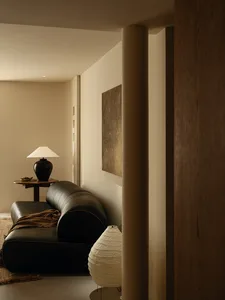 Dimly lit living room with a black couch and a lamp on a nearby table, creating a cozy atmosphere