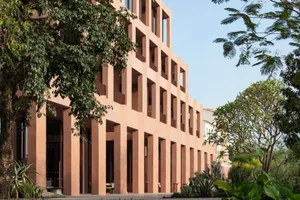 Large modern building with a curved structure and rows of windows, made of concrete, with natural light and a sophisticated atmosphere