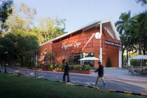 A modern restaurant with a red and orange color scheme, featuring a large dining area, bar, and potted plant outside