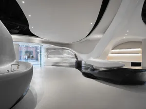 A large modern building with a white interior, featuring a curved open space with natural light and elegant design elements