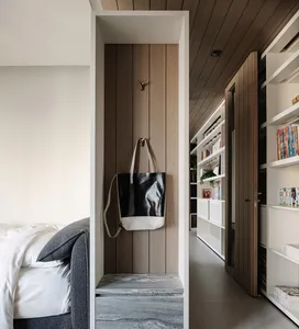 A minimalist bedroom with a bed, bookshelf, and closet, featuring white walls, a clean and bright appearance, and a modern style