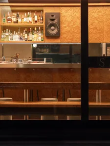 A cozy bar with a wooden counter and a variety of liquor bottles displayed, set in a restaurant or similar establishment