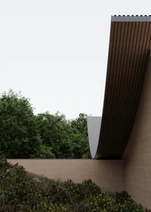 Photograph of a modern building with a curved roof, concrete exterior, and natural light from above