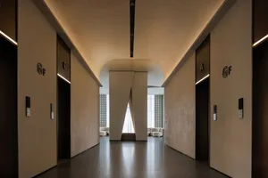 A large white room with a high ceiling, lined with doors and featuring a large window, creating a clean and spacious atmosphere