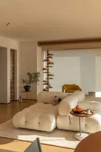 Cozy living room with a white sofa, a yellow chair, a dining table, a potted plant, and a vase, with a warm and inviting atmosphere