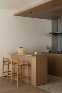 Modern kitchen with wooden cabinets, a wooden island, a sink, a stove, and a refrigerator, with two chairs and bright, well-lit atmosphere