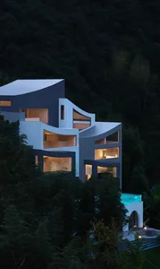 Large modern house with a curved structure, a pool in the backyard, surrounded by trees, with a luxurious and contemporary style