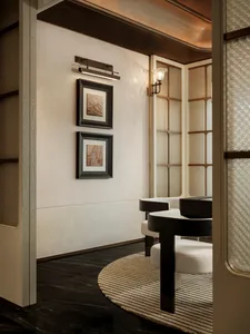 A dimly lit dining area with a wooden table and chairs, surrounded by a predominantly white room