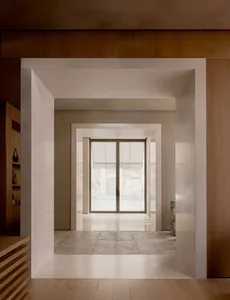 Well-lit room with a tile floor, wooden walls, and an open doorway leading to a hallway