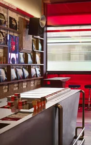 A modern bar with a red counter and walls, featuring a window with natural light and various items on display