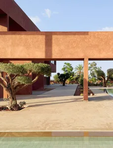 A residential outdoor area with a red building and a tree in the foreground, set against a warm and inviting background with a pool in the backyard