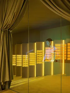 A well-lit store display featuring a man looking at various pairs of sunglasses in a glass case