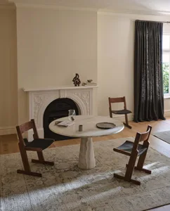 Cozy living room with a white fireplace, a table, two chairs, and a vase, creating a comfortable space for relaxation and socializing
