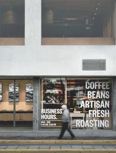 A modern coffee shop with a glass window display, well-lit interior, and furniture, creating a welcoming atmosphere