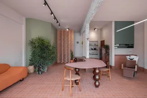 A modern restaurant with a large dining table, potted plants, and soft warm lighting creating a welcoming atmosphere