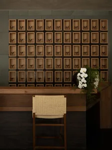 A warm and inviting hotel lobby with a wooden desk, chair, and decorative wine glasses, set against a neutral background